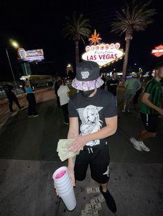 a young man is standing on the street with a bucket and money in his hand