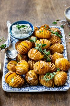 there is a plate full of baked potatoes with dip in the middle and two small bowls on the side