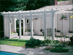 a white pergola sitting on top of a lush green field next to a swimming pool