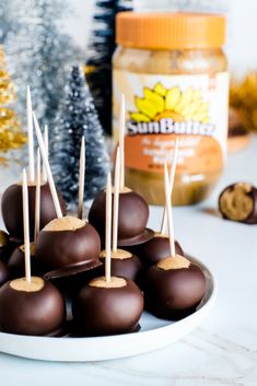 chocolate covered candies are on a plate with candy sticks in the foreground and gold decorations behind them