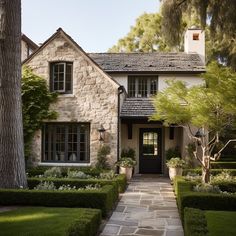 a stone house with trimmed hedges and trees