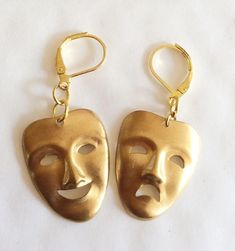 "A fabulous pair of handmade Happy and Sad Faces earrings Theatre Masks Comedy and Tragedy gold tone in raw brass Simple, charming dangle earrings for pierced ears with nickel free lever back fittings These lovely face earrings are an unusual pair of statement earrings The photo doesn't do them justice. The detail on the faces are fabulous Raw brass has the colour of 9ct gold without the price tag !  See also other earrings in this style faces / masks in silver tone, faces / masks in gold tone.  All finishes are available in happy and sad versions. Happy to put together any combination - just let me know I can also make screw fitting earrings for non pierced ears,   for an additional £1 See also the faces available as a bracelet in any combination of happy /sad charms with the finish you w Gold Novelty Earrings For Gifts, Gold Novelty Drop Earrings, Gold Novelty Dangle Jewelry, Novelty Gold Dangle Jewelry, Novelty Gold Nickel-free Earrings, Nickel-free Gold Novelty Earrings, Nickel-free Novelty Gold Earrings, Gold Novelty Pierced Earrings, Handmade Gold Novelty Jewelry