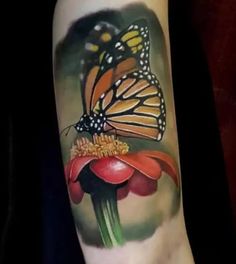 a tattoo with a butterfly on top of a flower and an orange flower in the middle