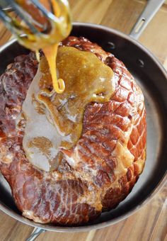 someone is pouring sauce on some meat in a pan