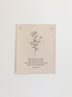 a white wall hanging with a black and white quote on it that says, the grass wishes, but the world of our god will not give us flowers