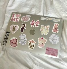 an apple laptop covered in stickers on a bed