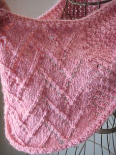 a pink knitted shawl sitting on top of a wire rack