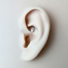 an ear with a diamond in it on a white surface and the top part is made out of plastic