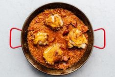 a pan filled with food sitting on top of a white counter next to a red spatula