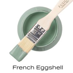 a paint brush with the words french eggshell painted on it's side, in front of a green plate