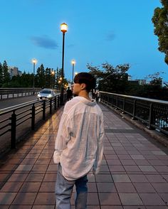 a man walking down a sidewalk next to a street light