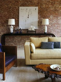 a living room with two couches and a table in front of the brick wall