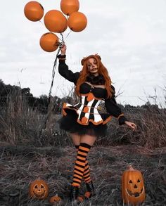 a woman dressed up as a witch with pumpkins in her hand and holding balloons