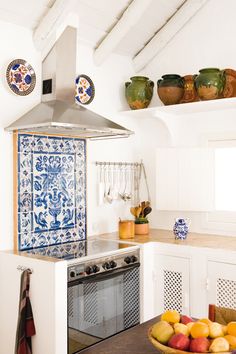 a kitchen with blue and white tiles on the wall, an oven hood over the stove