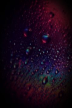 drops of water on a black surface with red, blue and green colors in the background