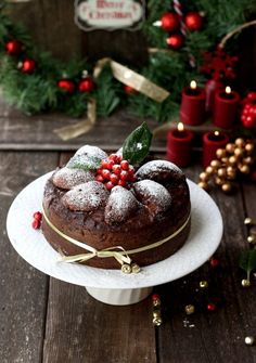 a bundt cake on a white plate with holly and red berries around the edges