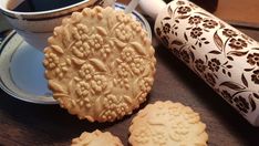 some cookies are on a plate next to a cup of coffee and a rolling pin