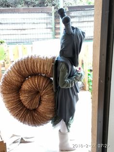 a statue is holding a large coil in front of a door that leads to a patio