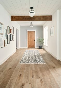 an empty room with white walls and wood flooring on the side, along with framed pictures hanging on the wall