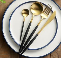 a white plate topped with black and gold utensils next to a fork and knife