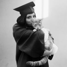 a woman wearing a graduation cap and gown holding a cat