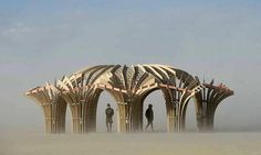 two men are standing in front of a structure made out of wooden planks on a foggy day