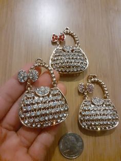 three small purses are being held in front of a coin on a wooden table