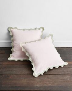 two white pillows sitting on top of a wooden floor next to a wall and wood floor