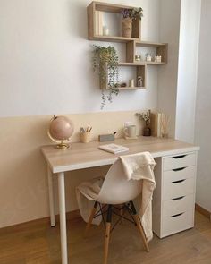 a white desk topped with a laptop computer next to a shelf filled with potted plants