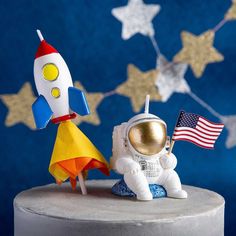 an astronaut and flag on top of a cake with stars in the sky behind it