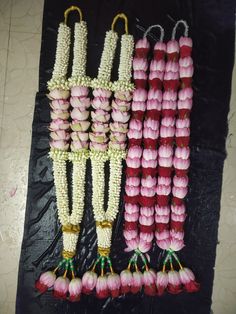 some pink and white flowers hanging from strings on a black surface with other items in the background