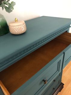 a blue dresser with drawers and a vase on top