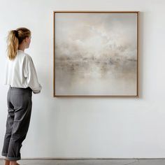 a woman standing in front of a painting on the wall with her back to the camera