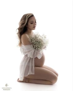 a pregnant woman sitting on the floor holding a bouquet of flowers