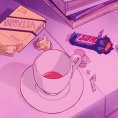 a cup of tea next to some books and candy on a table with other items