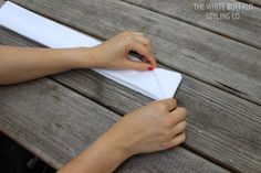 a person writing on a piece of paper while sitting on a bench with their hands