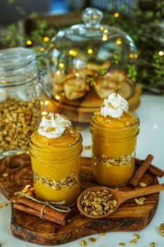 two jars filled with food sitting on top of a wooden tray next to cinnamon sticks