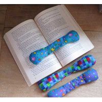 an open book sitting next to two colorful dog bone toys on top of a wooden table