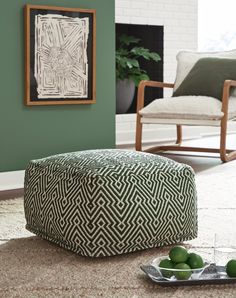 a green and white ottoman sitting on top of a floor next to two limes