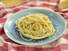 a blue plate topped with spaghetti on top of a red and white checkered table cloth