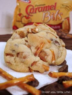 a chocolate chip cookie and some pretzels on a white towel next to a bag of caramel bits