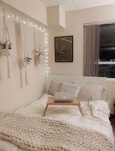 a bed with a laptop on top of it in a room filled with string lights