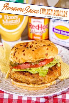 a chicken burger with lettuce, tomato and cheese on a plate next to potato chips