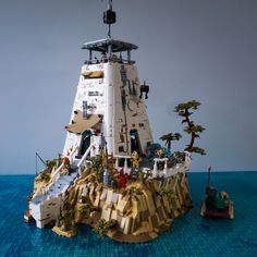 a lego model of a space ship on the water with trees and people around it