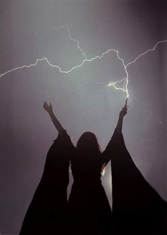 two women standing in front of a lightning storm