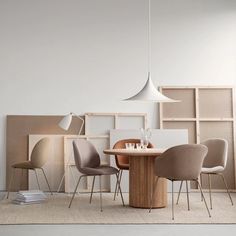 a dining room table surrounded by chairs and bookshelves in front of a white wall