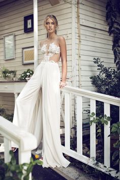 a woman in a white dress standing on a porch with her hand on her hip