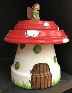 a red and white mushroom house with a fairy on top