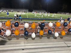 a group of people standing on top of a soccer field next to a fence covered in balloons