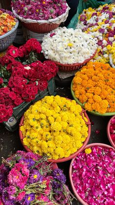 many different colored flowers in baskets on the ground